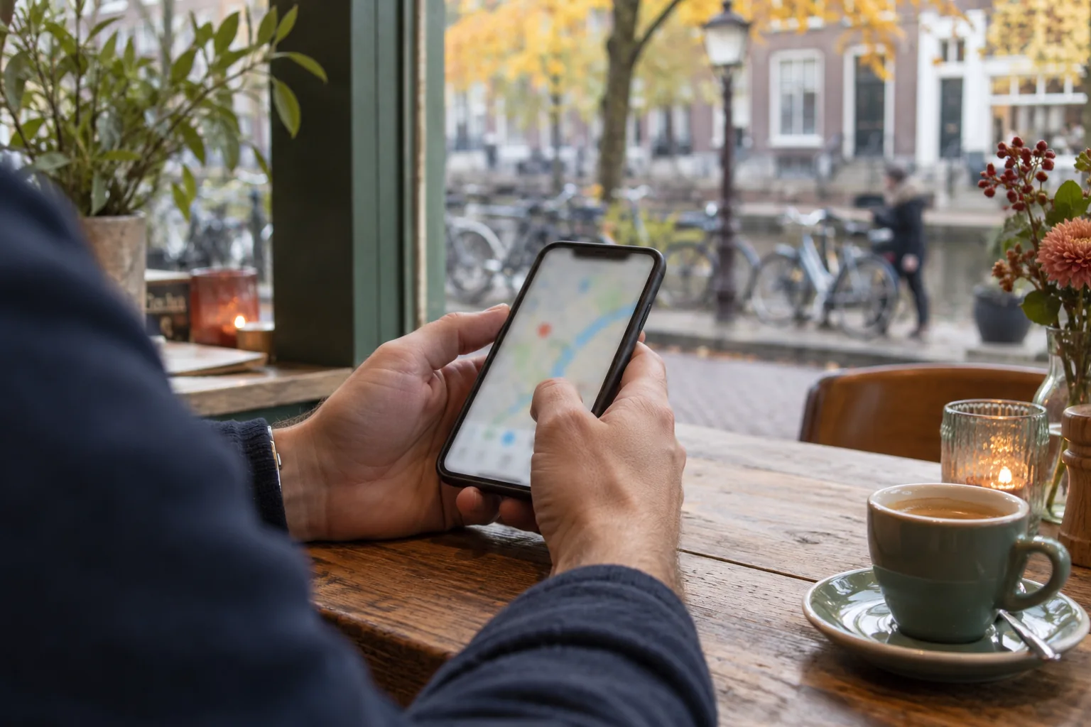 Handen houden een telefoon met een abstracte kaartweergave bij een raam aan een straat.
