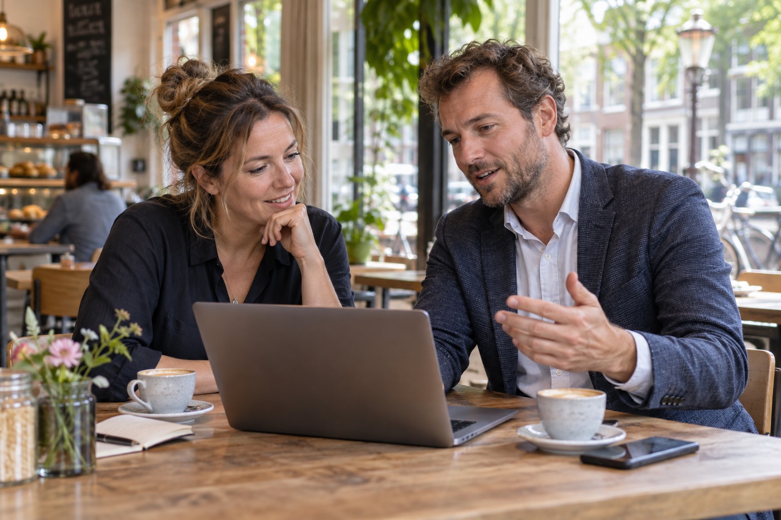 Twee mensen bespreken de website van een ondernemer op een laptop.